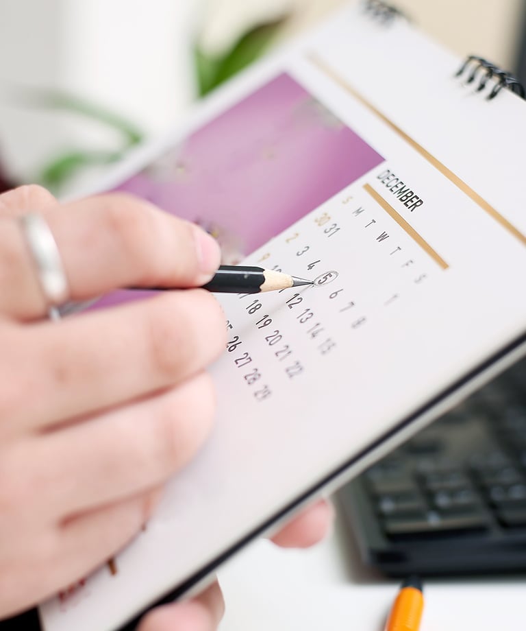 A person circling a date on a monthly calendar