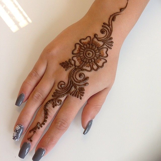 a woman's hand with henna tattoo of a flower design