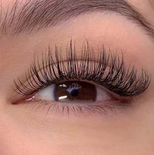 a woman with classic eyelash extensions and looks long eyelashes and lashes on her eyes