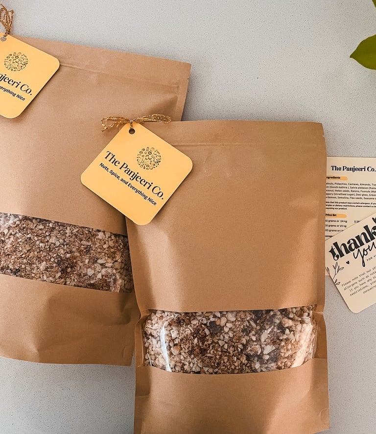 Two sealed, recyclable brown paper bags filled with handcrafted subcontinental granola (Panjeeri).