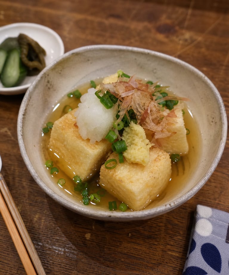 Agedashi Do-fu, a Japanese dish of deep-fried tofu in dashi broth with green onions and bonito flakes.