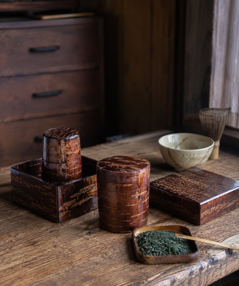 Traditional Japanese cherry bark tea canisters and matcha green tea set on a rustic wooden table.