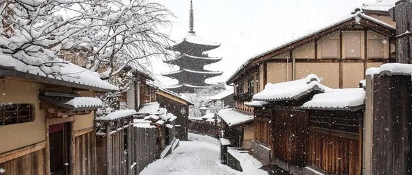 Snow-covered street in Kyoto's historic Higashiyama district with the Yasaka Pagoda in the background.