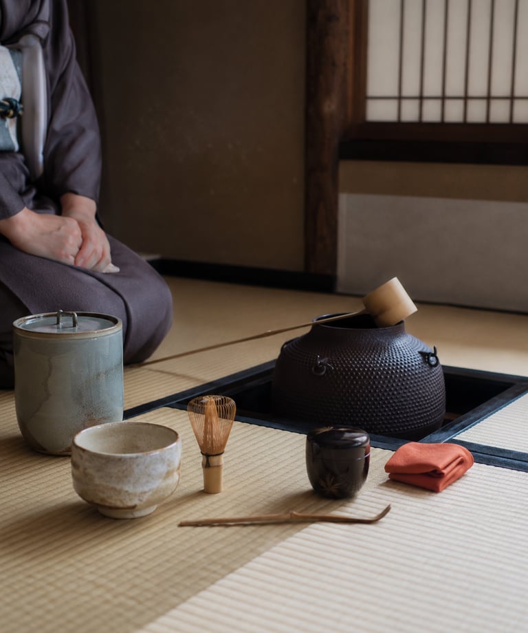 Traditional Japanese tea ceremony set on a tatami mat with matcha whisk, bowl, and iron kettle.