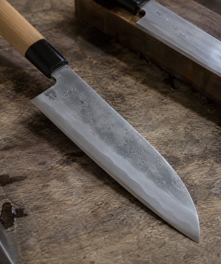 Hand-forged Japanese Santoku kitchen knife with carbon steel blade on a wooden cutting board.