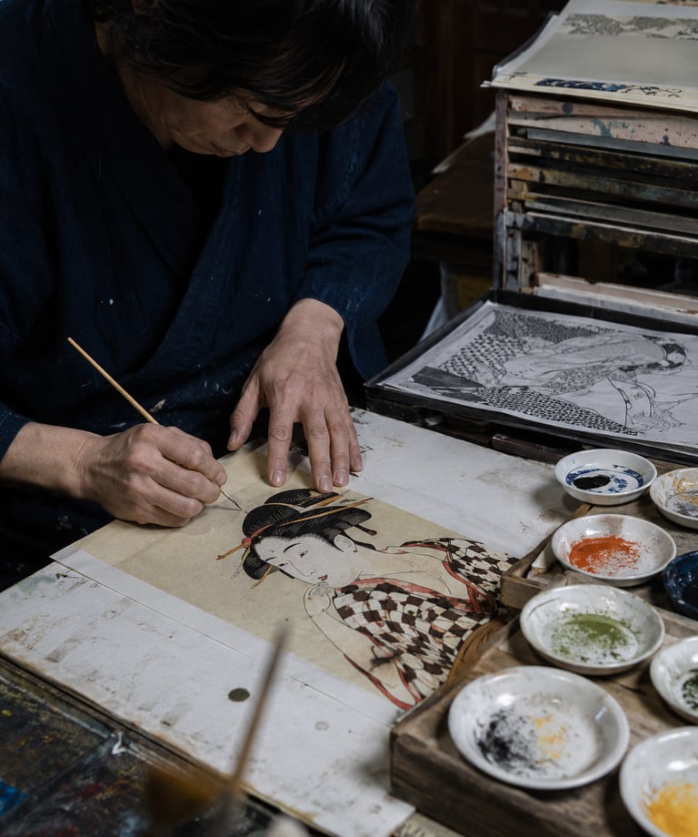 A Japanese artist hand-painting a traditional Ukiyo-e woodblock print portrait of a woman.