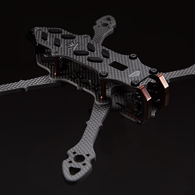 A lightweight carbon fiber FPV racing drone frame with a matte finish on a dark background.