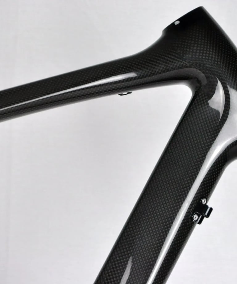 Close-up of a lightweight carbon fiber bicycle frame showing the woven texture and head tube.