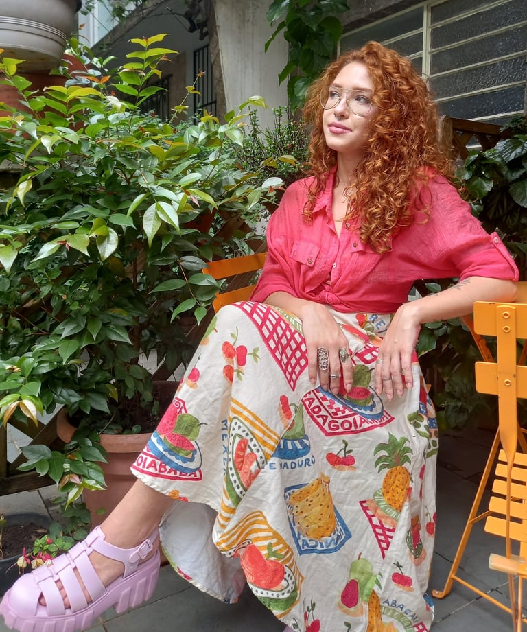 Sabrina Tibursky sentada de pernas cruzadas em frente a plantas