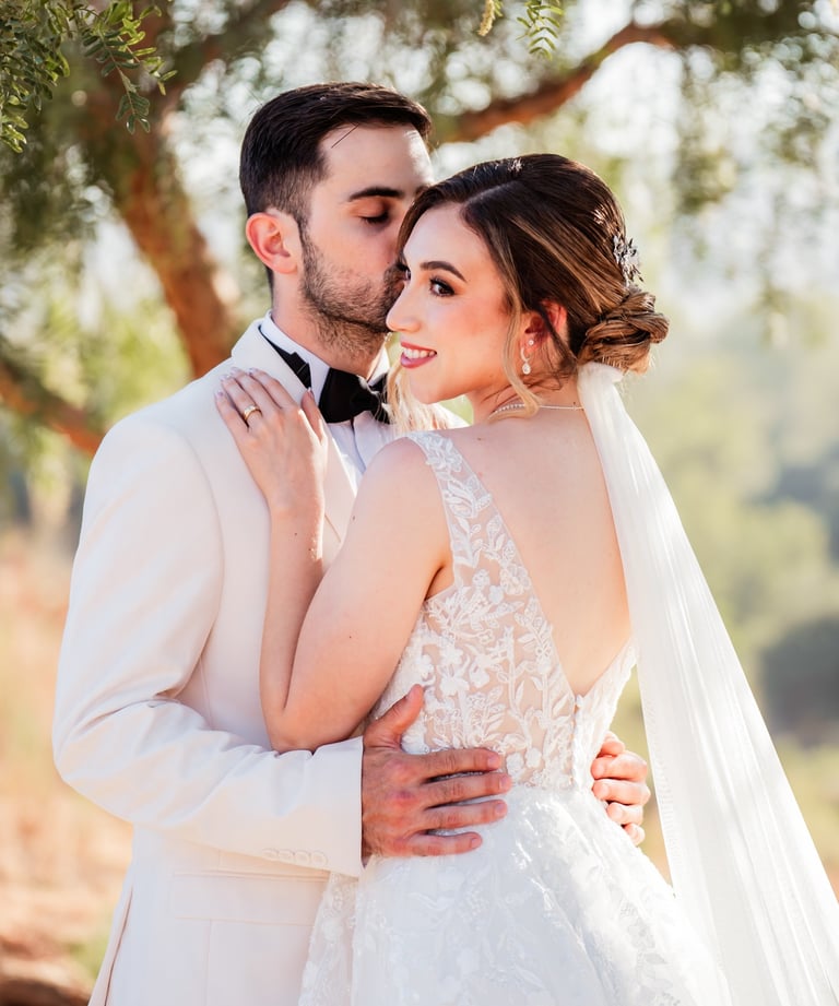 a bride and groom standing in front of a tree