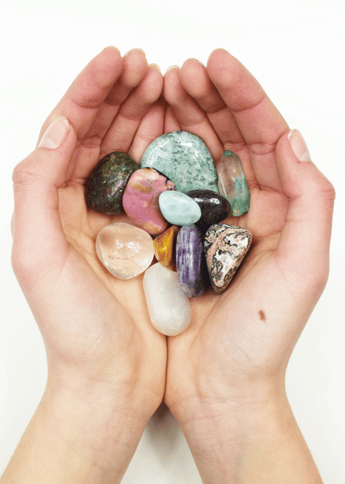 hand holding various colourful crystals