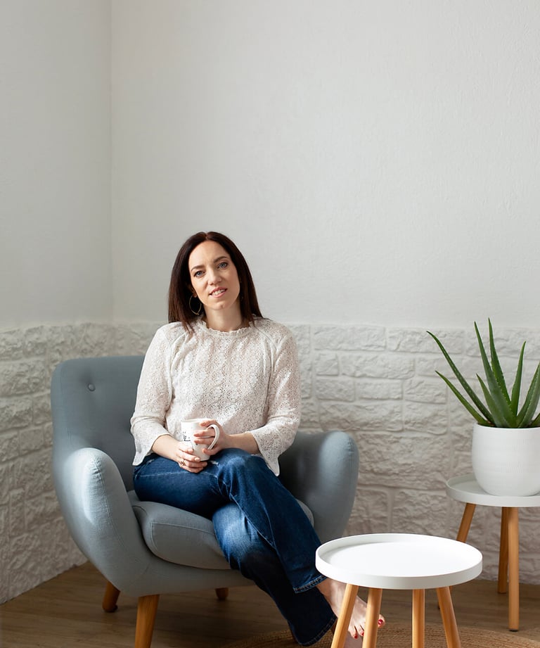 a woman sitting in a chair with a plant in front of her