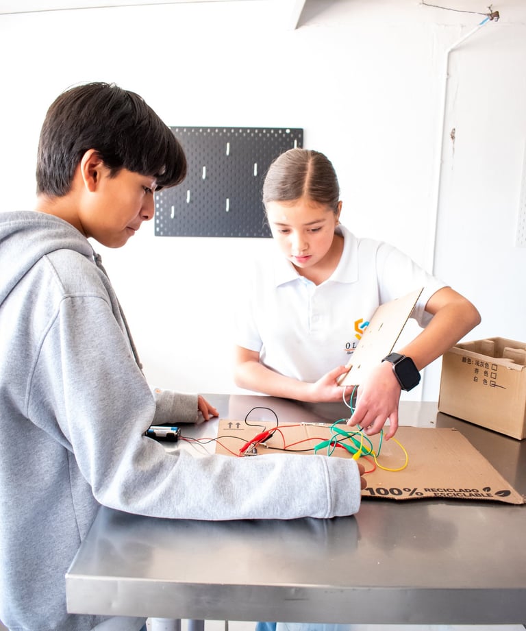 Students collaborating on a STEM project with an electrical circuit and wires in a classroom workshop.