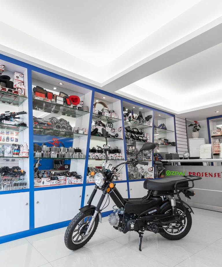 A modern motorcycle lights store featuring a moped and glass shelves stocked with spare accessories.