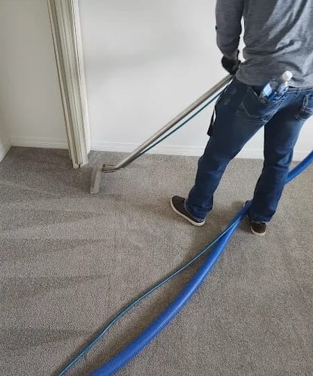 Technician steam cleaning carpet in Fort McMurray home.