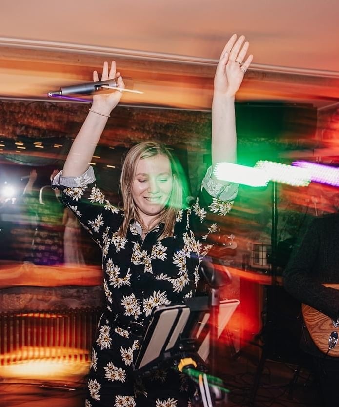 a woman in a floral jumpsuit dancing with a guitar at wedding party