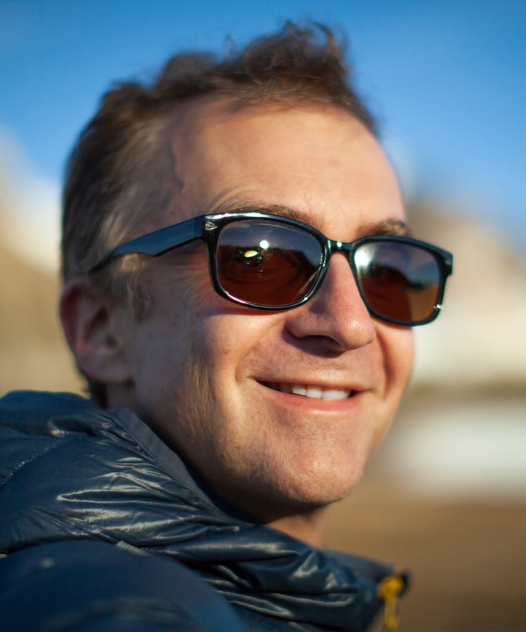 a man in sunglasses and a jacket is smiling