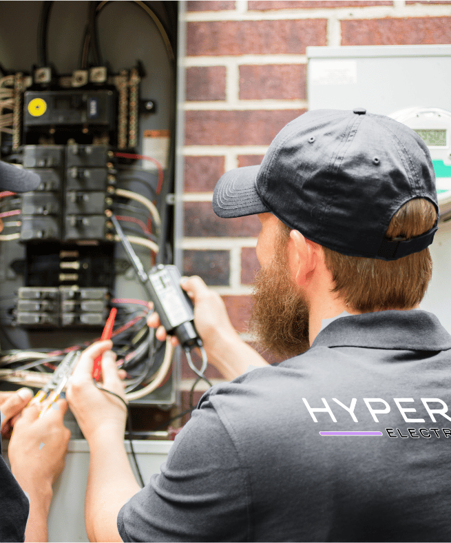 A Hyperion electrician checking an electrical service panel with a journeyman in training 