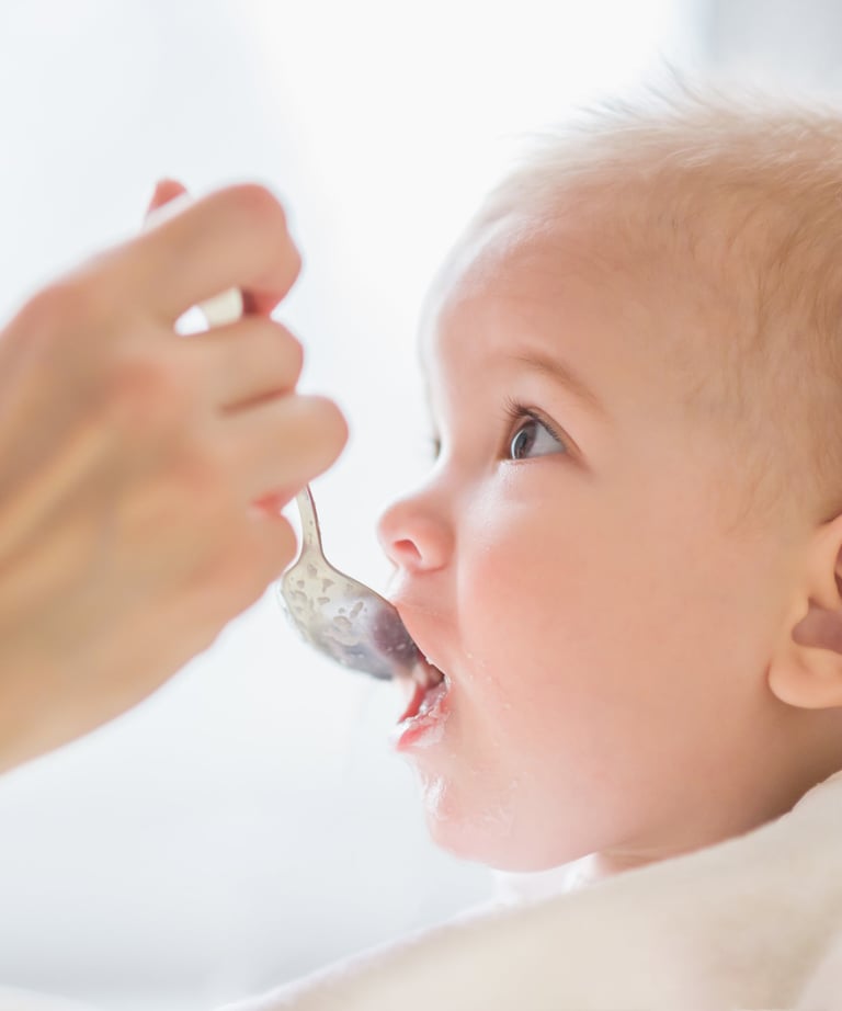 a baby is gets food with a spoon
