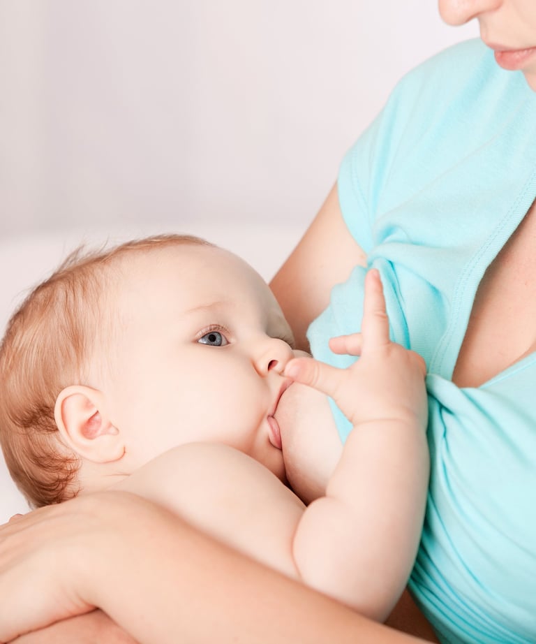 a woman breastfeeding a baby in a blue dress