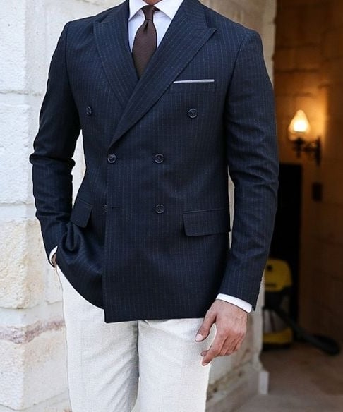 a man in a suit and tie is standing in front of a stone wall