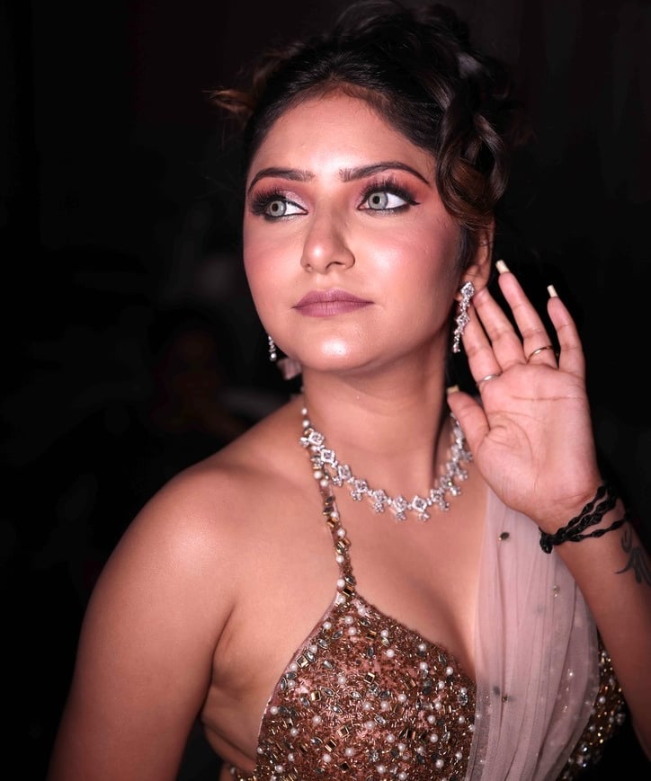 Indian woman with glam party makeup, smokey eyes, glowing skin, shimmering embellished blouse, and s
