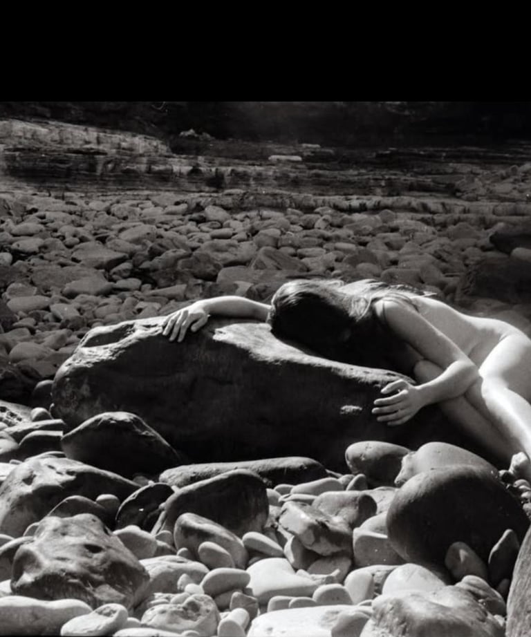 A woman holding and being held by smooth solid rocks surrounded by smaller rock fragments