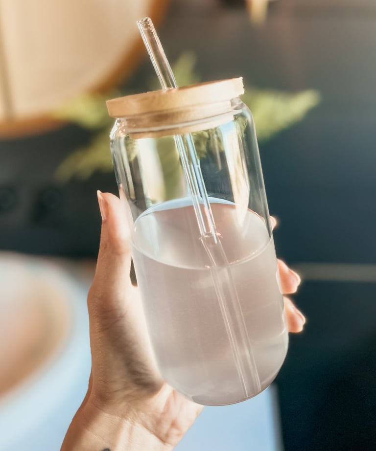 Glass cup with wooden lid and glass straw, filled with a wellness drink