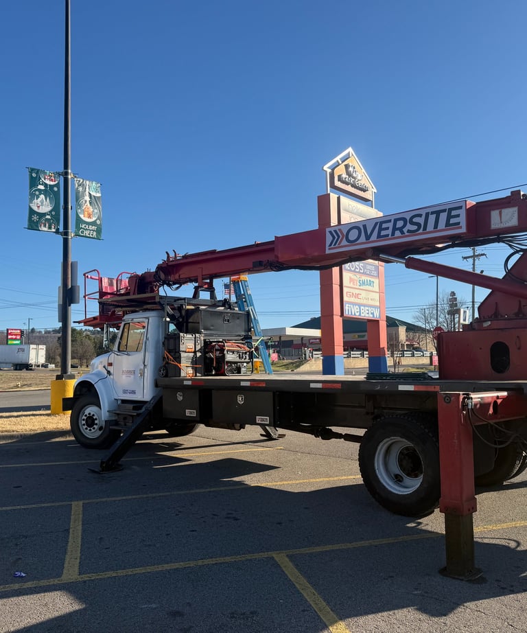A commercial Oversite bucket truck parked in a shopping center lot for outdoor sign maintenance.