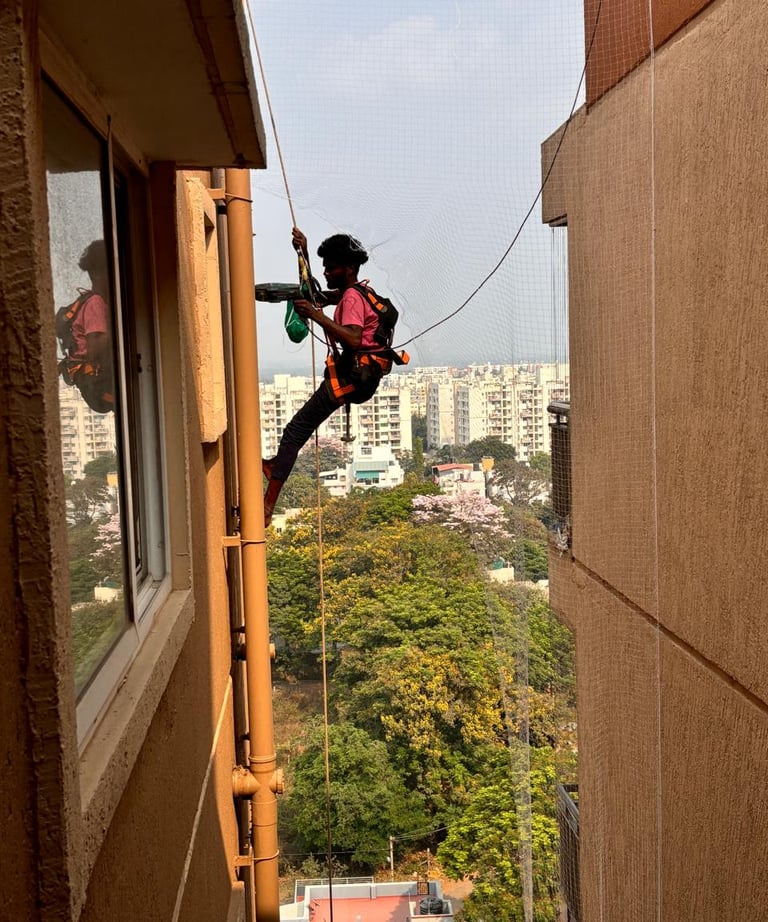 Wide shot of a residential building in Haralur with pigeon control nets visibly installed on ducts.