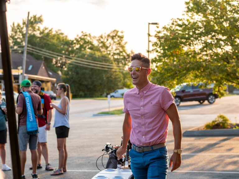 Lawrence wearing sunglasses, walking with his bike