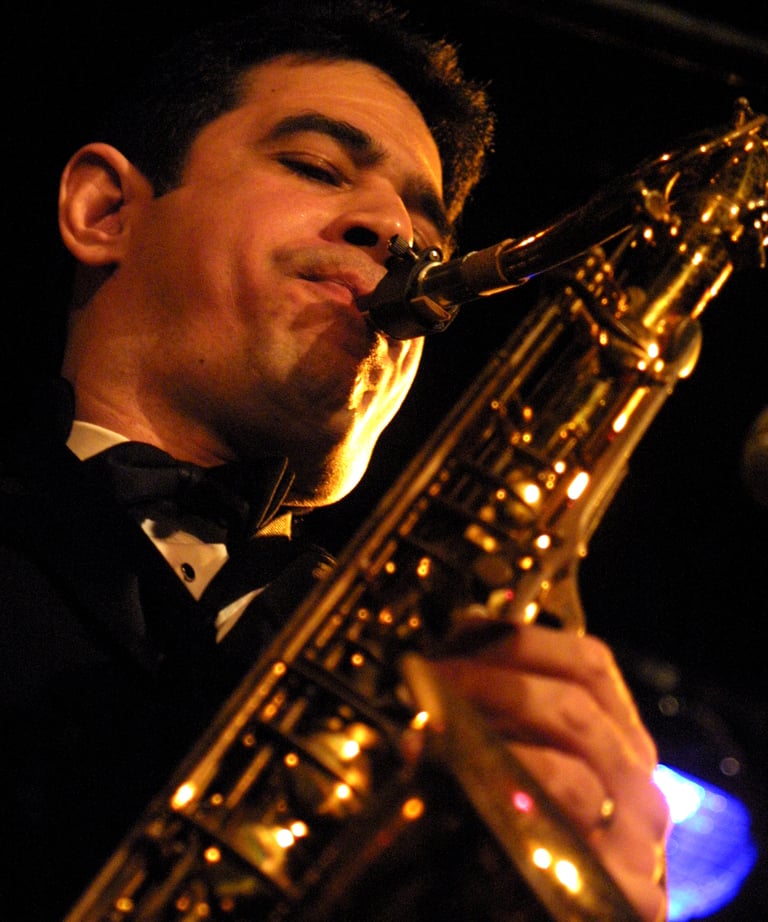 Maestro Bobby Ramirez in a tuxedo playing a saxophone