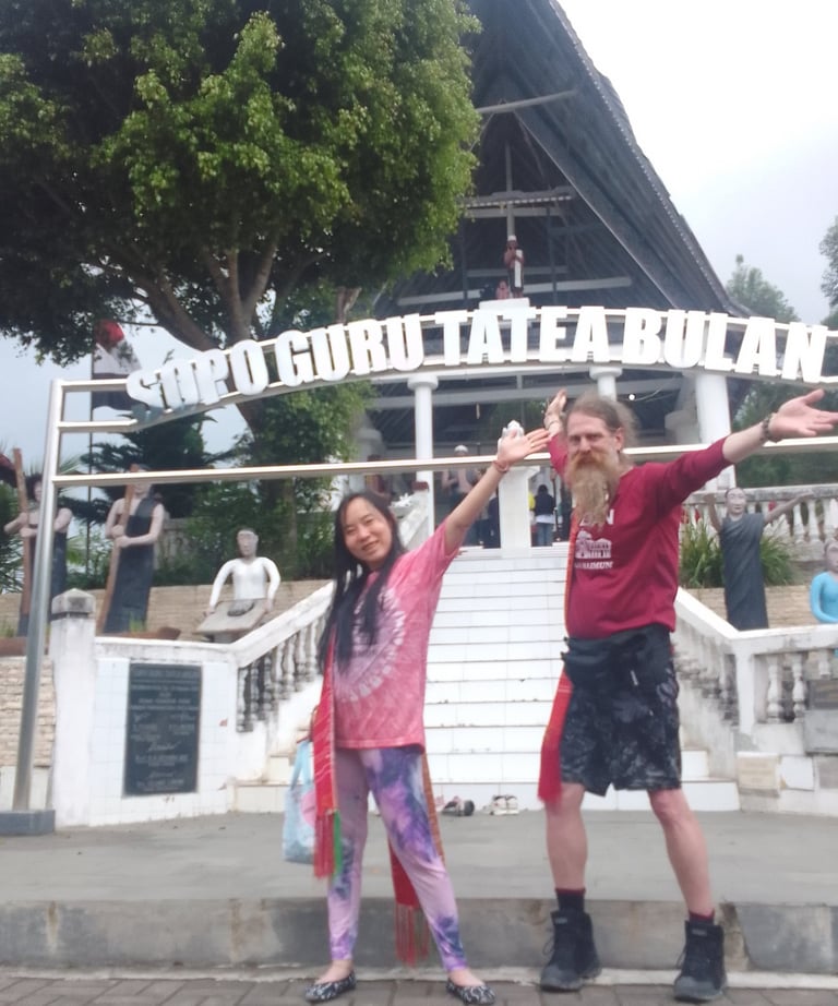 a woman and a man are joyful and smiling in front of an ancient shrine site in Sumatra