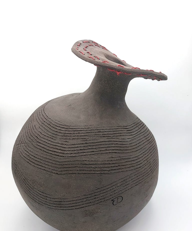 Estelle Del artiste sculpture représentant un pot en terre noire en déséquilibre