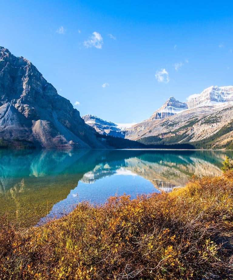Panoramic view of Bow Lake in Banff National Park with mountain reflections on turquoise water.