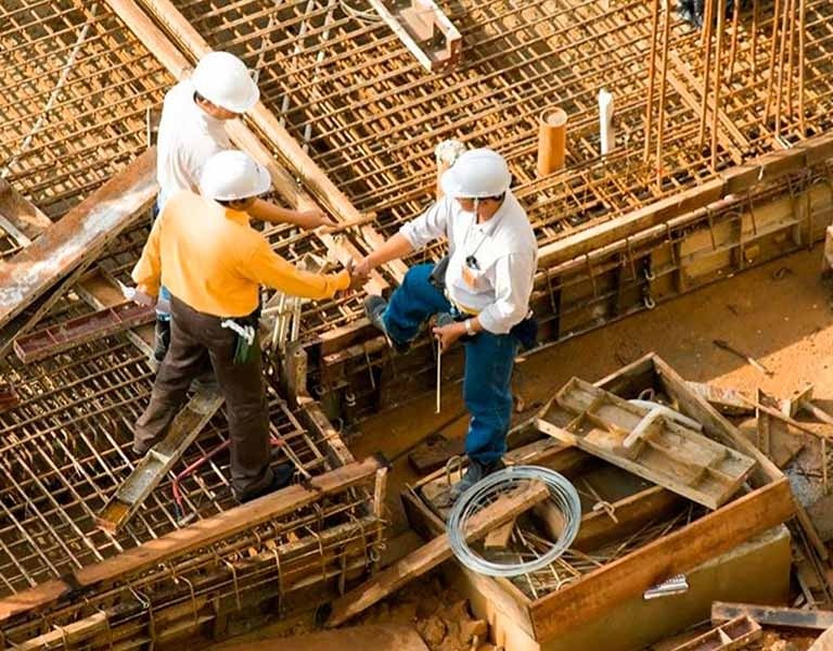 Profesionales revisando estructura en obra gris, reflejando ejecución de proyectos con calidad