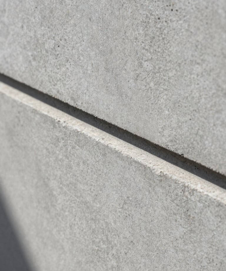Macro shot of concrete texture with a sharp shadow line, representing the minimalist and professional brand identity, medium gray.