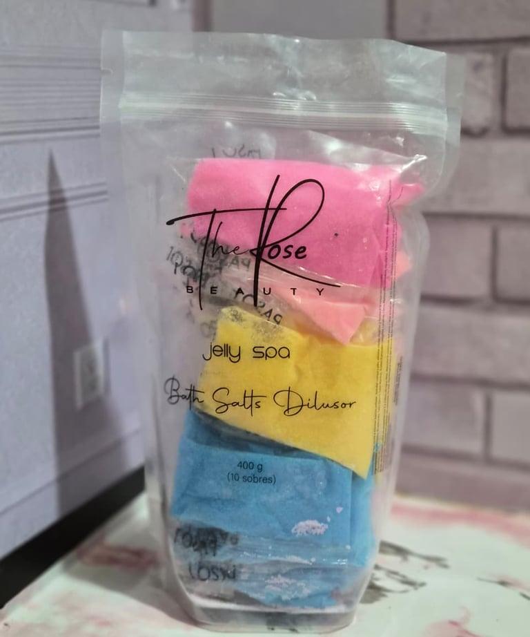 A clear bag of The Rose Beauty Jelly Spa bath salt dilutor packets in pink, yellow, and blue colors.