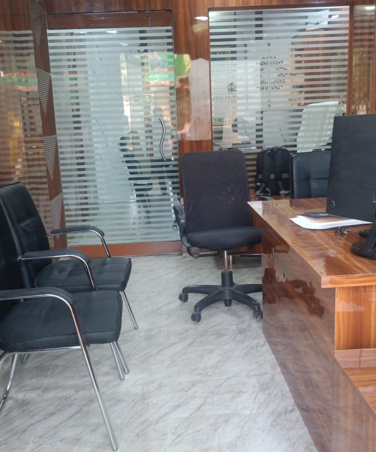 Professional office interior featuring a wooden desk, black rolling chairs, and glass partition doors.