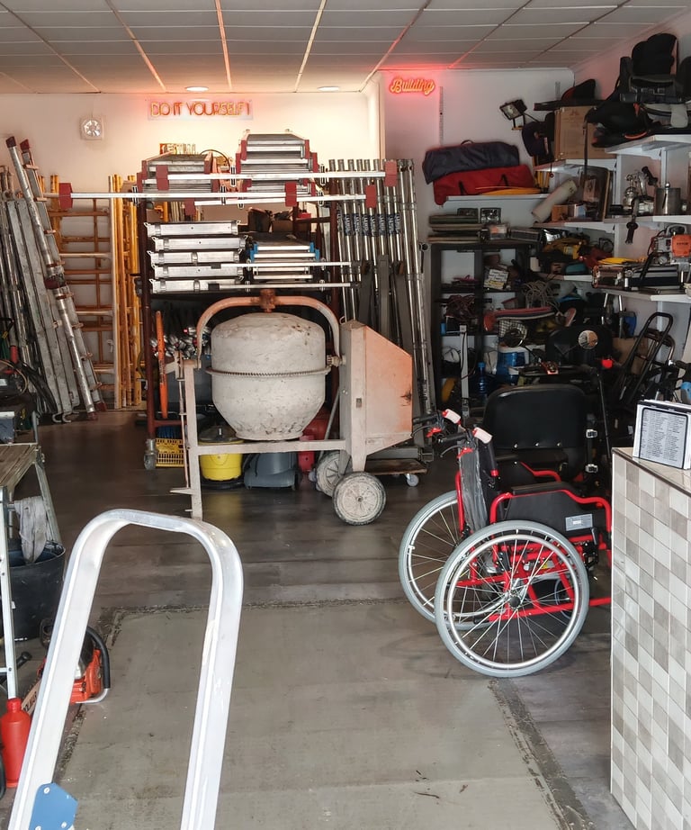 A well-stocked tool rental shop interior featuring cement mixers, ladders, and power tools on shelves.