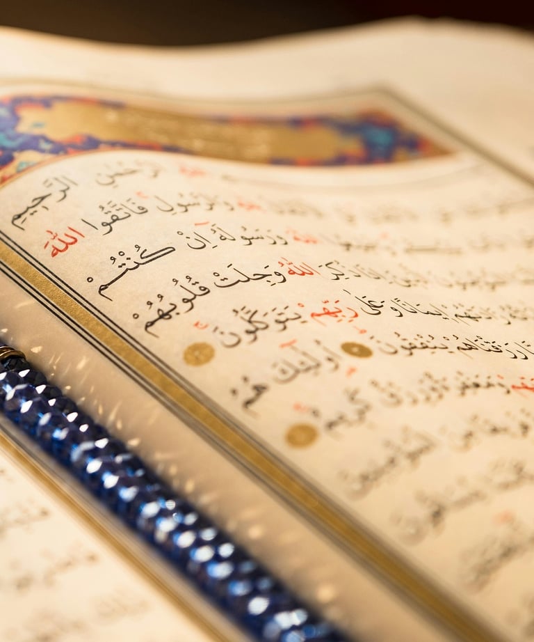Close-up of an open Holy Quran with Arabic calligraphy and blue prayer beads on a page.