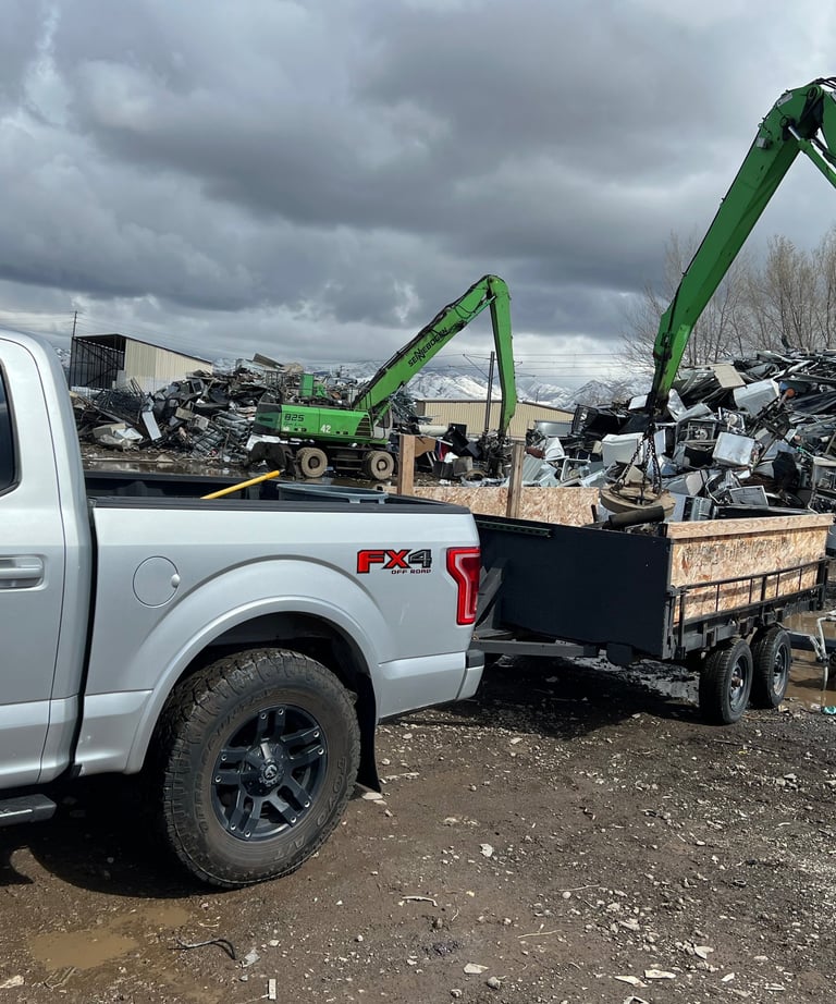 Truck and trailer being unloaded by a crane with a magnet at the metal recycling center