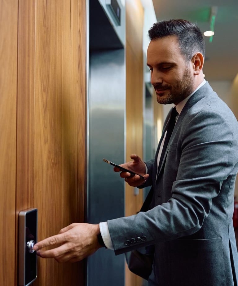 a man in a suit and tie is holding a cell phone and pushing the elevator button to request a ride