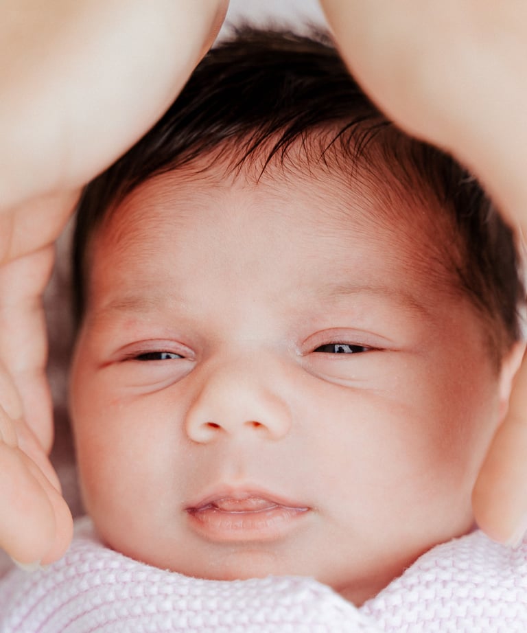 le visage d'un nouveau-né entre des mains