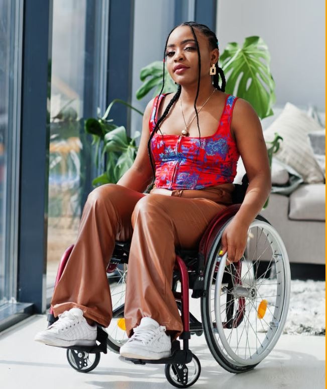 a woman in a wheelchair with a red top and brown pants