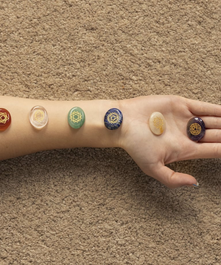Bras allongé avec pierres de chakras alignées pour un soin énergétique et un rééquilibrage énergétiq