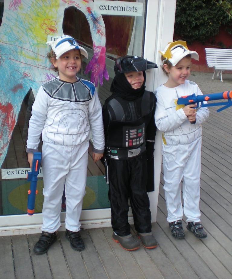 Three young children dressed in Star Wars costumes posing outside with toy blasters.