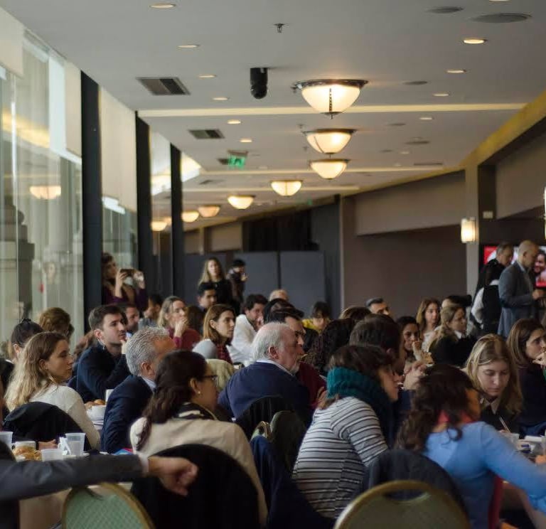 a group of people sitting at tables in a room Haciendo gestión