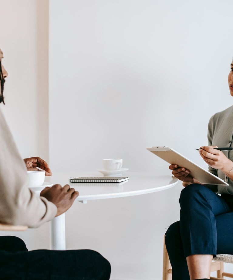 Une femme assise à une table et un homme sur une chaise en train de discuter