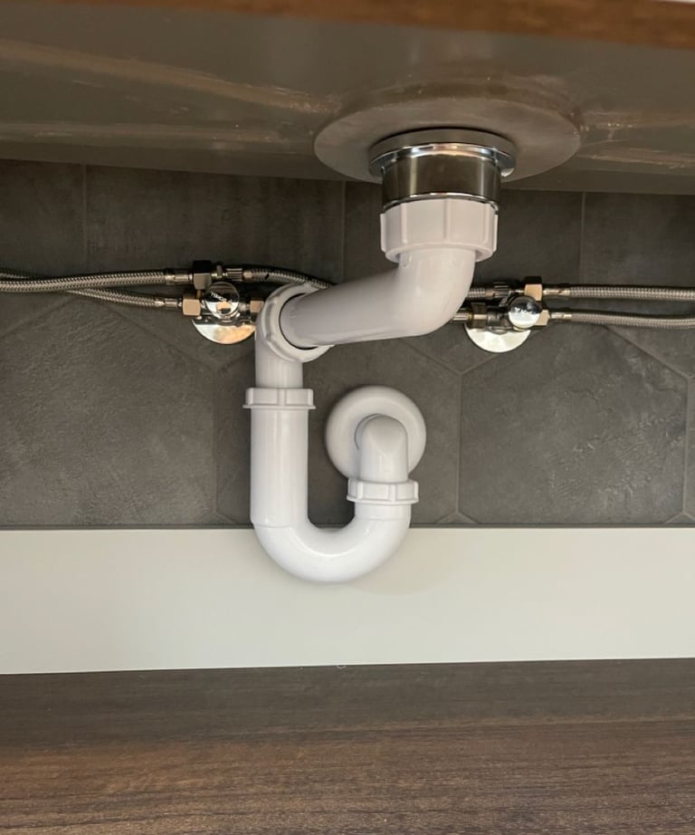 Installation d’un siphon sous évier avec raccordements flexibles pour l’arrivée d’eau